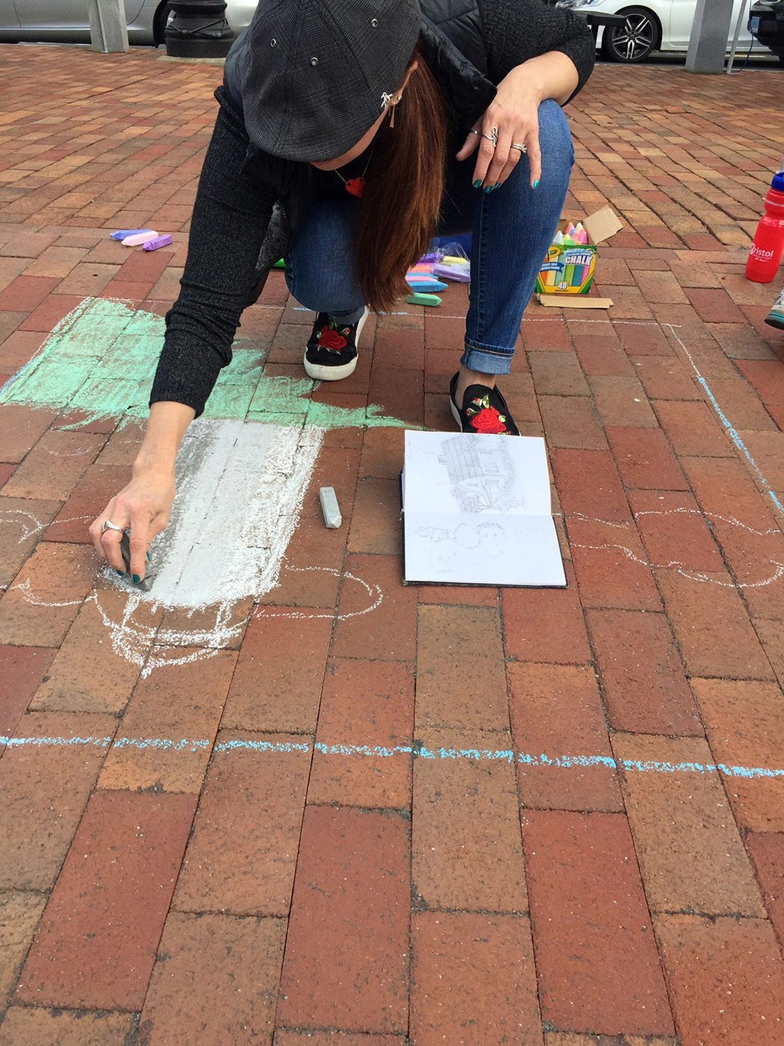 Artist creating chalk art on brick pavement